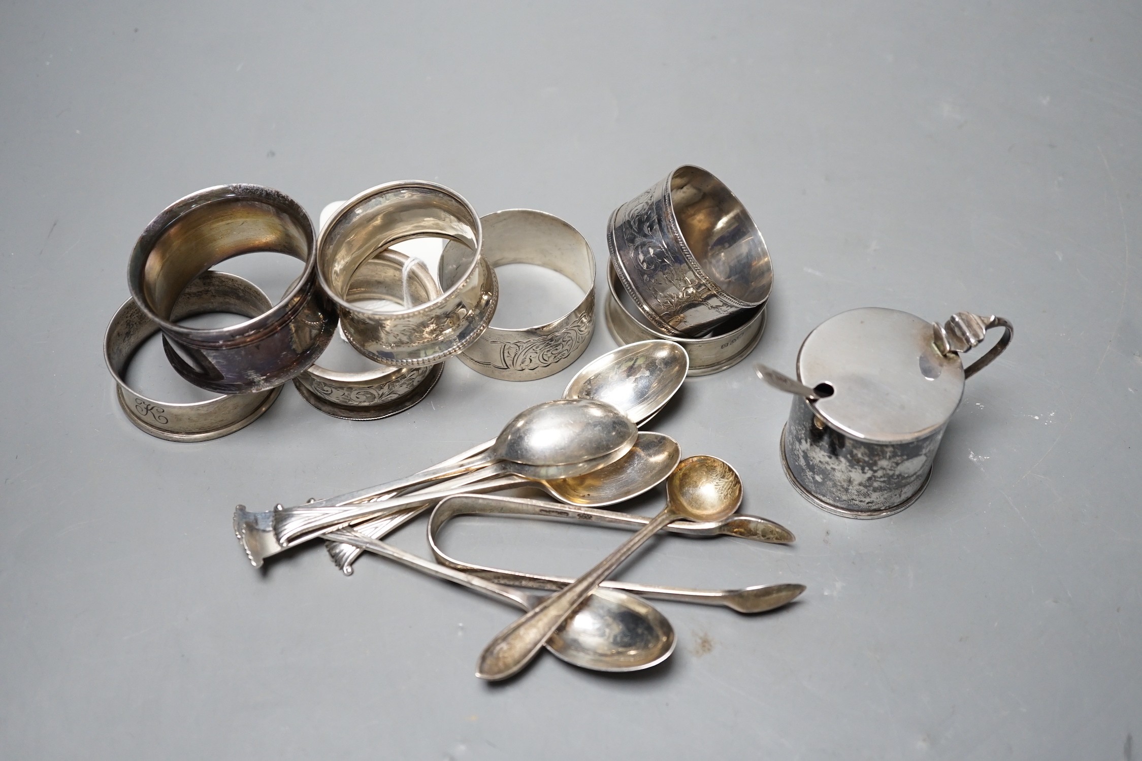 An Edwardian silver mustard pot, Birmingham, 1905, a set of six 'Onslow' pattern silver teaspoons by William Hutton & Sons, London, 1903, a pair of silver sugar tongs, a silver condiment spoons, six assorted silver napki